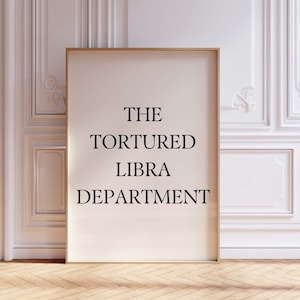 May include: A framed print with the text "THE TORTURED LIBRA DEPARTMENT" in black lettering on a white background.