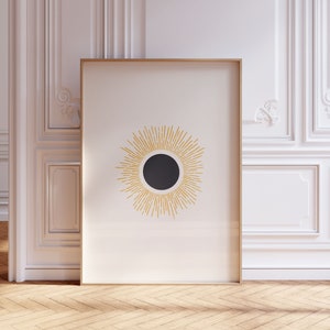 Peut inclure: Une impression encadrée avec un design minimaliste d'un soleil avec un centre noir et des rayons jaunes sur un fond blanc.