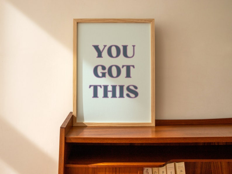 May include: A framed print with a light blue background and the text "YOU GOT THIS" in dark blue letters with a pink outline.