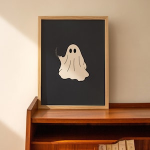 May include: A framed print of a white ghost with two eyes and a cigarette in its hand, on a dark blue background.