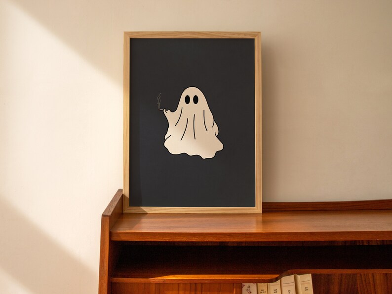 May include: A framed print of a white ghost with two eyes and a cigarette in its hand, on a dark blue background.