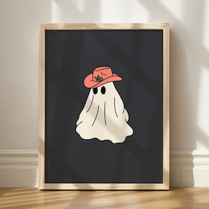 May include: A black and white illustration of a ghost wearing a red cowboy hat with a green leaf detail. The ghost is framed in a wooden frame.