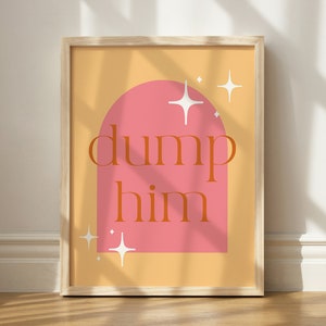 Pode incluir: Uma impressão emoldurada com fundo pêssego e um arco rosa. O arco tem o texto "dump him" em laranja. Há estrelas brancas espalhadas ao redor do arco.