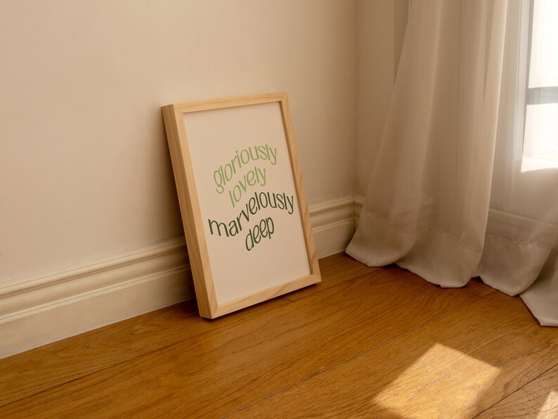 May include: A wooden framed print with the words "gloriously lovely marvelously deep" written in green on a cream background.