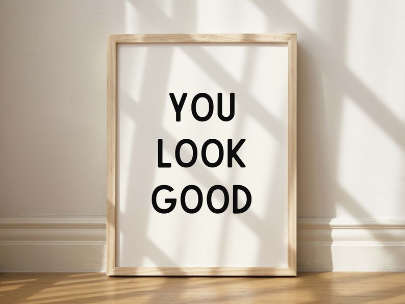 May include: A framed print with the text "YOU LOOK GOOD" in black lettering on a white background.