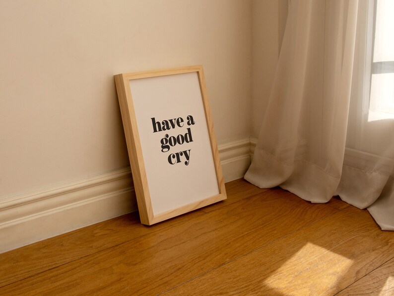 K&ouml;nnte beinhalten: Ein gerahmter Druck mit dem Text "have a good cry" in schwarzen Fettdruck auf wei&szlig;em Hintergrund. Der Rahmen ist aus hellem Holz und steht auf einem Holzboden.