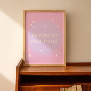 May include: A framed print with a pink and purple ombre background and white stars. The print says "be kind to your mind".