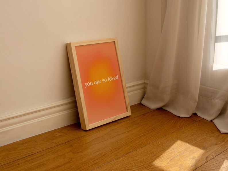 May include: A framed print with a peach and orange gradient background and the text "you are so loved" in white.