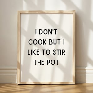 Könnte beinhalten: Ein gerahmter Druck mit dem Text "Ich koche nicht, aber ich mag es, den Topf zu rühren" in schwarzen Buchstaben auf weißem Hintergrund.