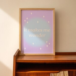 Puede incluir: Una impresi&oacute;n enmarcada con un fondo degradado de azul claro y morado. La impresi&oacute;n presenta estrellas blancas y el texto "it makes me wonder".