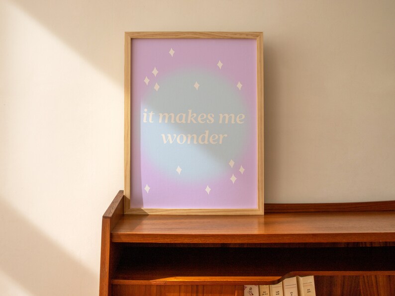Puede incluir: Una impresi&oacute;n enmarcada con un fondo degradado de azul claro y morado. La impresi&oacute;n presenta estrellas blancas y el texto "it makes me wonder".