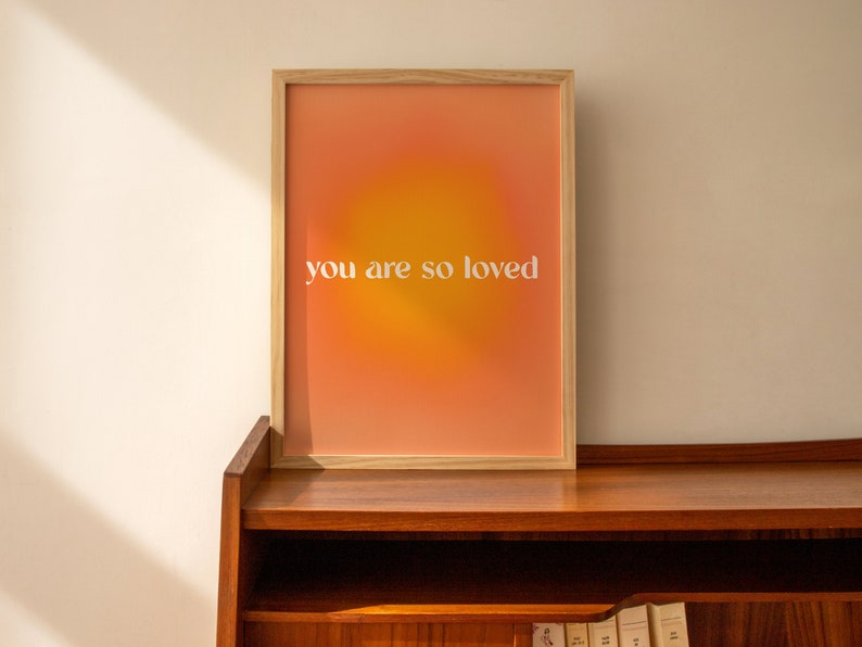 May include: A framed print with a gradient background of orange and yellow. The text "you are so loved" is printed in white on the print.