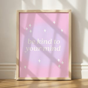 May include: A framed print with a pink and purple gradient background. The print features the text "be kind to your mind" in white lettering and small white diamond shapes scattered throughout the background.