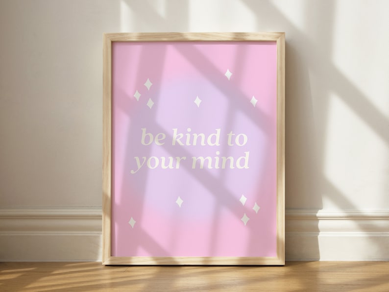 May include: A framed print with a pink and purple gradient background. The print features the text "be kind to your mind" in white lettering and small white diamond shapes scattered throughout the background.