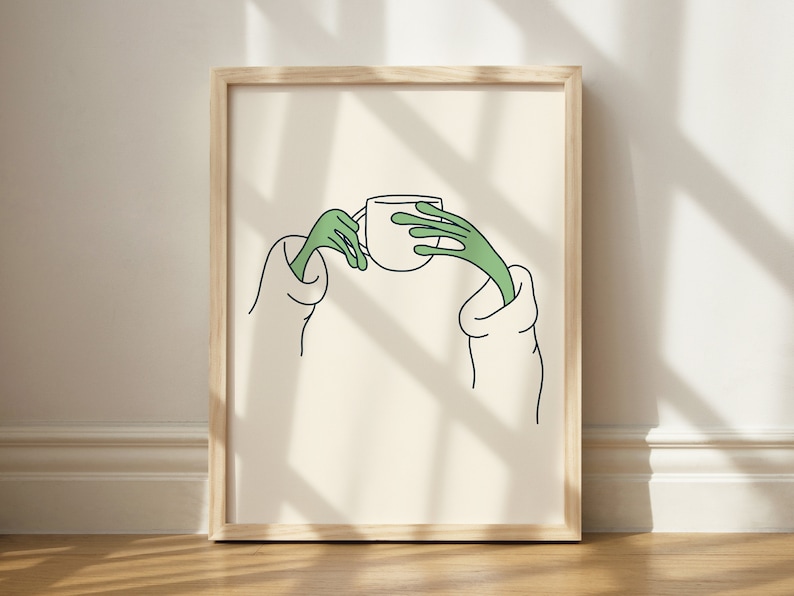 May include: A framed illustration of two green hands holding a white cup. The hands are drawn in a simple, cartoon style. The background is a light beige colour.