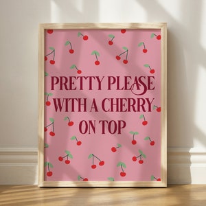May include: A pink framed print with a cherry pattern and the text "PRETTY PLEASE WITH A CHERRY ON TOP" in burgundy.