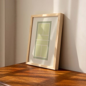 May include: A framed print of a tennis court in green and yellow colors. The frame is made of natural wood.