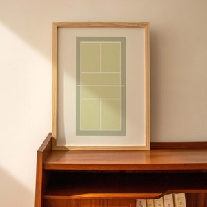 May include: A framed print of a tennis court in green and white colors. The frame is made of natural wood and the print is on white paper.