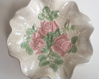 May include: A white ceramic bowl with a scalloped edge features a raised design of pink roses and green leaves.