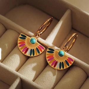 May include: Gold hoop earrings with a fan-shaped pendant. The pendant has a turquoise stone centre and colourful enamel accents in red, pink, orange, blue, and green. The earrings are presented in a beige jewellery box.