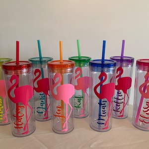 May include: Set of eight clear plastic tumblers with colorful lids and straws. Each tumbler features a pink flamingo silhouette and a personalized name, including "Melissa", "Haley", "Janis", "Jen", "Kat", "Micah", "Kellie", and "Elissa".