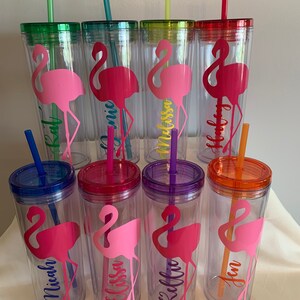 May include: Set of eight clear plastic tumblers with colorful lids and straws. Each tumbler features a pink flamingo silhouette and a personalized name, including:  'Kai', 'Monica', 'Melissa', 'Holly', 'Michaela', 'Elissa', 'Kellie', and 'Jen'.