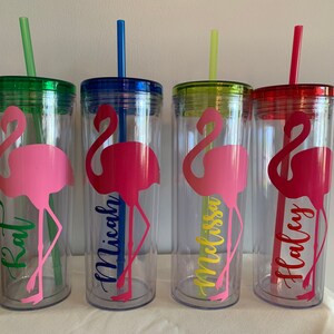 May include: Four clear plastic tumblers with pink flamingo designs and personalized names:  Kat, Micah, Melissa, and Haley. Each tumbler has a matching colored lid and straw.