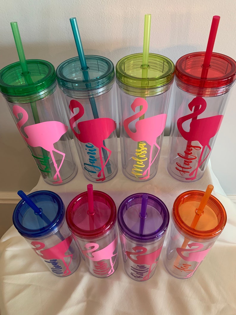 May include: Set of ten clear plastic tumblers with colorful lids and straws. Each tumbler features a pink flamingo silhouette and a personalized name, including "Jamie", "Melissa", "Holly", "Mia", "Ellie", "Kallie", and "Ann".