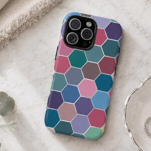 May include: A smartphone case featuring a repeating geometric honeycomb pattern in various shades of blue, pink, purple, and teal. The design consists of solid-colored hexagons separated by thin white lines, covering the entire back of the case.