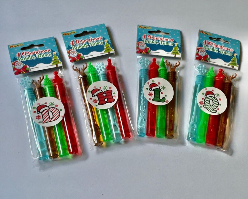 May include: Four sets of Christmas bubble wands, each set includes four wands with different colors and designs. The wands are decorated with snowflakes, reindeer, and Santa hats. The packaging says "4 Christmas Bubble Tubes".