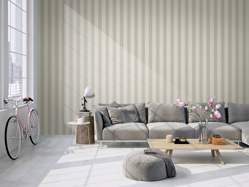K&ouml;nnte beinhalten: Tapete mit vertikalem Streifenmuster in abwechselnden Nuancen von hellem Beige und Creme. Das Design hat eine subtile, texturierte Optik, die an einen gewebten Stoff erinnert und einen neutralen Hintergrund f&uuml;r Wohnr&auml;ume schafft.
