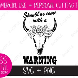 May include: Black and white silhouette of a cow skull with floral accents. The text "Should've come with a WARNING" is below the skull. The text "SVG + PNG" is below the warning.
