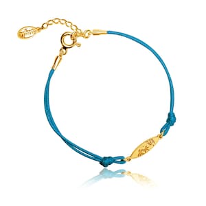 Op de afbeelding: Een turquoise blauwe koordarmband met een gouden bedel met een palmboomontwerp. De armband heeft een gouden sluiting en is verstelbaar.