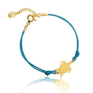 Peut inclure: Un bracelet en or avec un pendentif en forme de tortue et un cordon turquoise. Le bracelet est doté d'un fermoir en or et est réglable.