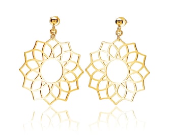 May include: A pair of gold-toned earrings with a delicate, circular, mandala-like design. The earrings are made of metal and have a dangling, drop-style design.