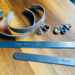 May include: Two silver bracelets with engraved text, "lips dream" and "one flesh, one end". A third silver bracelet with the text "Insert Quote Here!" is also shown. The bracelets have small silver charms with clear and colored gemstones.
