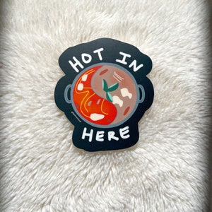 May include: Black and white sticker with a red and brown illustration of a pot with food inside. The text "HOT IN HERE" is written around the pot.