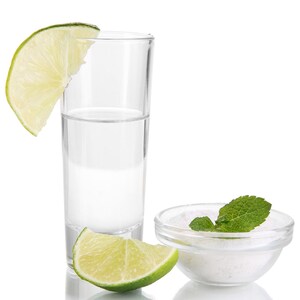 May include: A clear shot glass filled with a clear liquid, a lime wedge, and a small bowl of white salt with a sprig of mint on top.