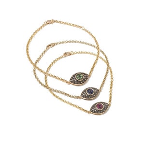 May include: Three gold chain bracelets with a small evil eye charm. Each charm is set with pave diamonds and a single center stone: green, blue, and red.
