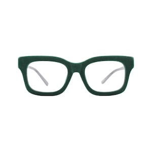 May include: A pair of eyeglasses featuring a thick, dark green velvet-textured frame with a square shape. The lenses are clear and transparent, and the temples are thin and silver-toned, extending from the sides of the frame.