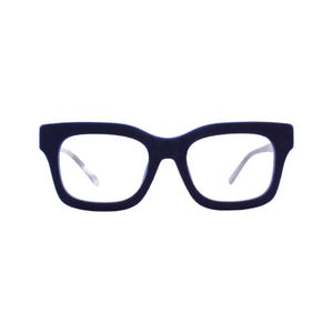 May include: A pair of dark navy blue eyeglasses with a thick, rounded square frame and clear lenses. The frame features a matte, textured finish, and the thin, metallic-toned temples are visible extending from the sides of the front frame piece.