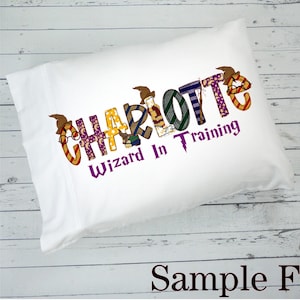 May include: White pillowcase with the name "Charlotte" spelled out in colorful letters with a wizard hat on each letter. The text "Wizard in Training" is below the name in purple.