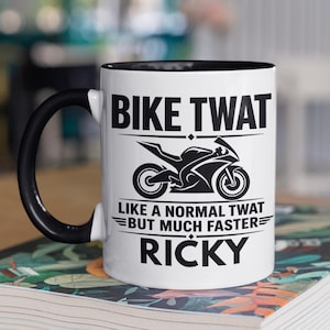 May include: A white ceramic mug with a black handle and interior. The front features a black graphic of a sport motorcycle centred between the text BIKE TWAT, LIKE A NORMAL TWAT BUT MUCH FASTER, and the name RICKY printed in bold black lettering.