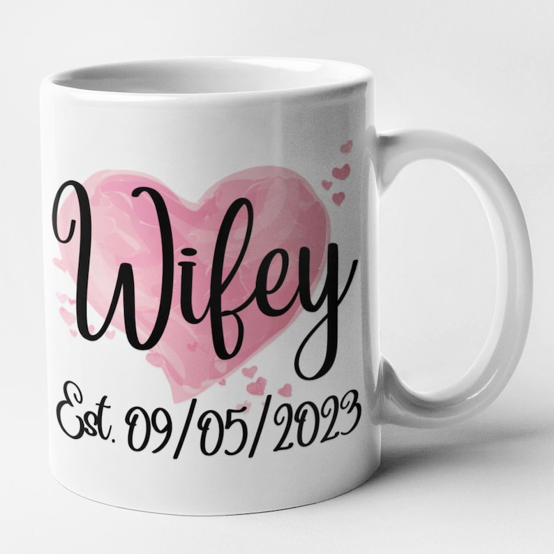 May include: White ceramic mug with a pink watercolor heart that says "Wifey" and the text "Est. 09/05/2023" below the heart.
