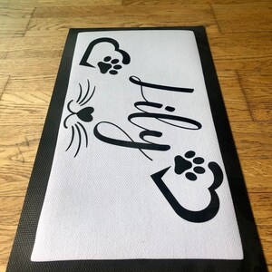 May include: Black and white doormat with the word "Paw-ty" in a decorative font. The doormat has two paw prints and two hearts with paw prints inside.