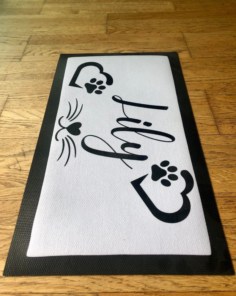 May include: Black and white doormat with the word "Paw-ty" in a decorative font. The doormat has two paw prints and two hearts with paw prints inside.
