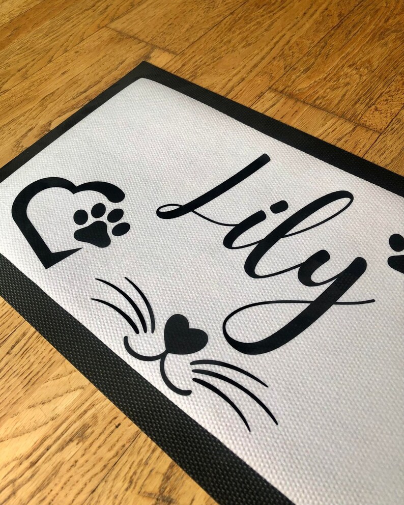May include: Black and white doormat with a black heart and paw print, black cat whiskers and a heart, and the name "Lily" in black cursive lettering.