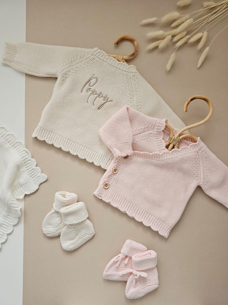 Personalised Floral Initial Knitted Baby Cardigan with embroidered monogram letter and delicate flower detail, perfect for baby girls. Ideal as a baby announcement jumper, luxury baby shower gift, or new baby present. This soft, handmade cotton sweater is a keepsake piece for newborn photos or first outfit. A thoughtful personalised gift for new parents, featuring custom initials and timeless knit design. Monogram baby sweater made with love.