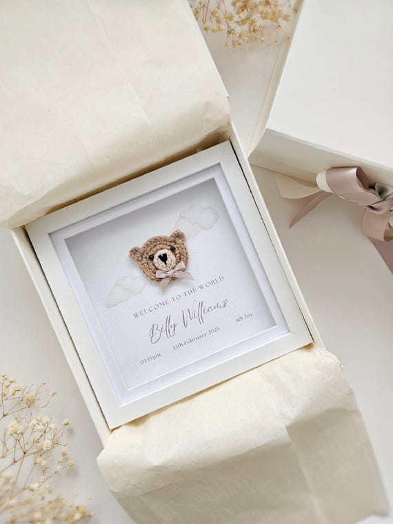 A framed crochet teddy bear with the baby's birth details woven into the design — 399 favorites don't lie, this is a genuinely charming, handmade keepsake that lives on the nursery wall forever.