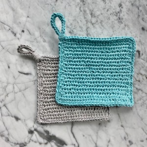 May include: Two crocheted pot holders, one in light gray and one in light blue, with a loop handle on each.
